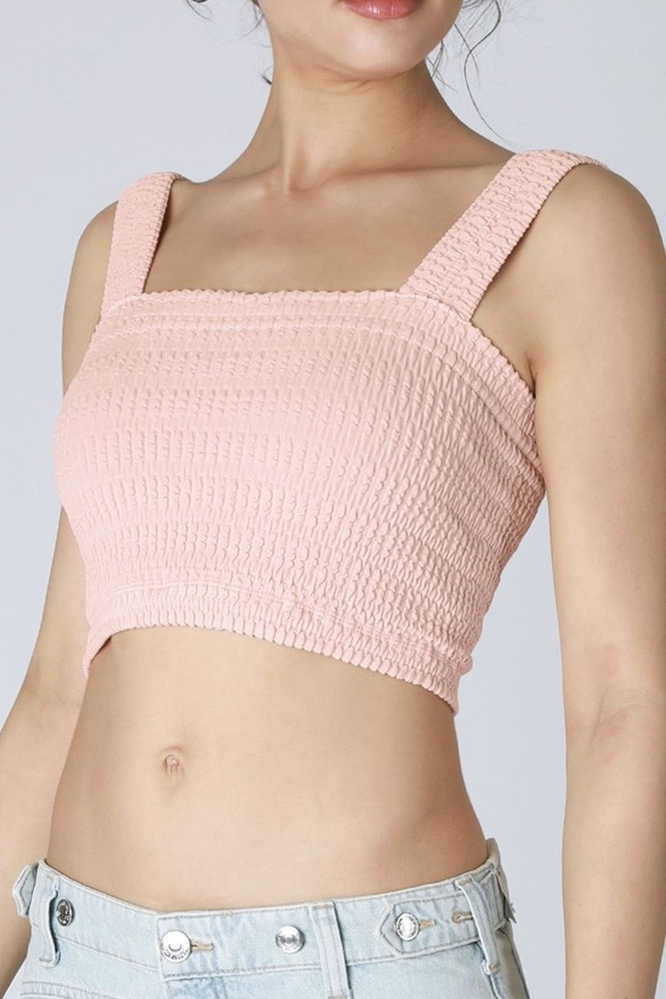 Person wearing a pink textured crop top against a plain background