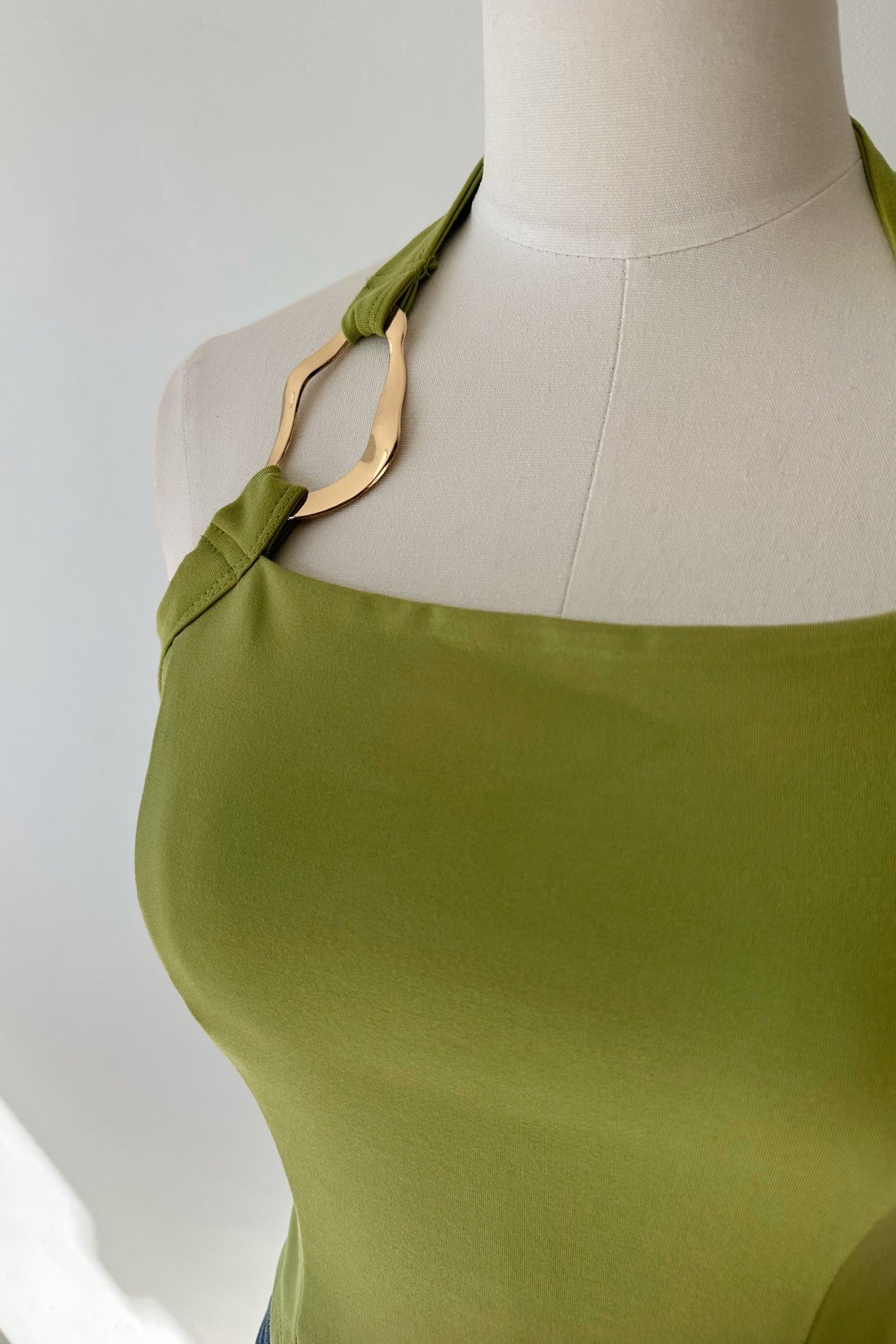 Green dress on a mannequin with a plain background