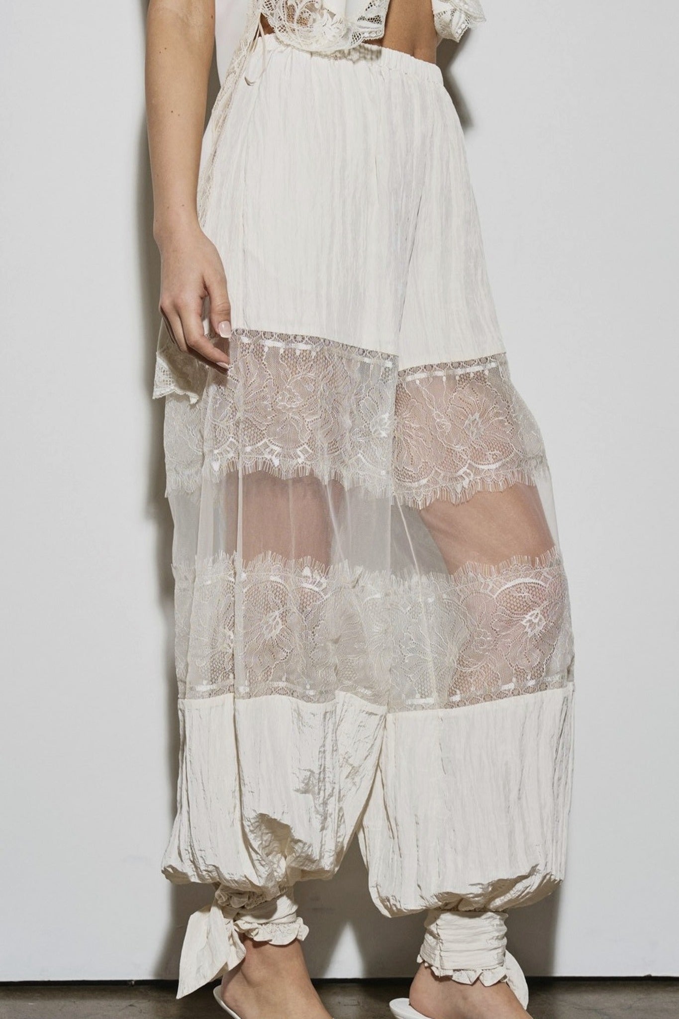 White lace dress with sheer overlay on a plain background