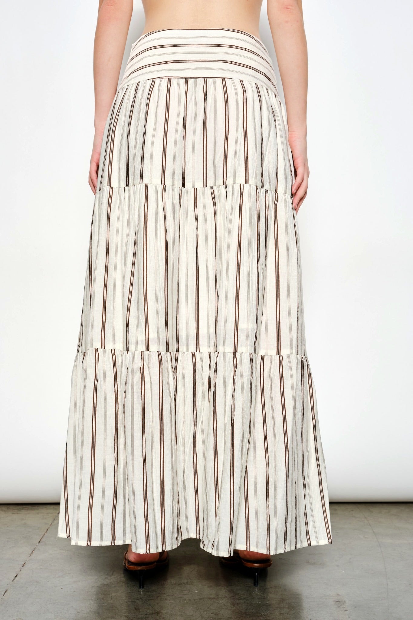 Long striped skirt worn by a person on a plain background