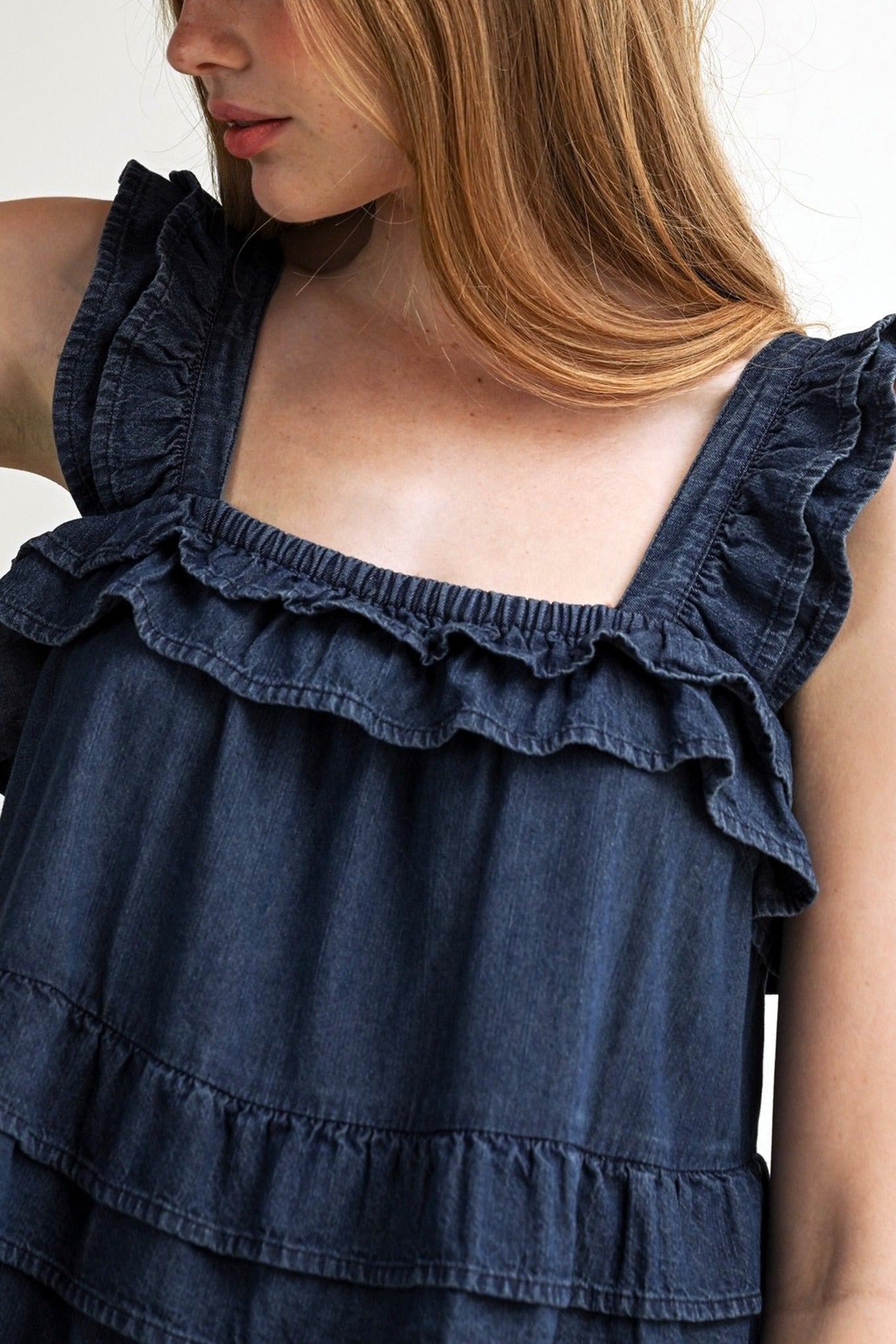 Navy blue ruffled dress worn by a person on a white background