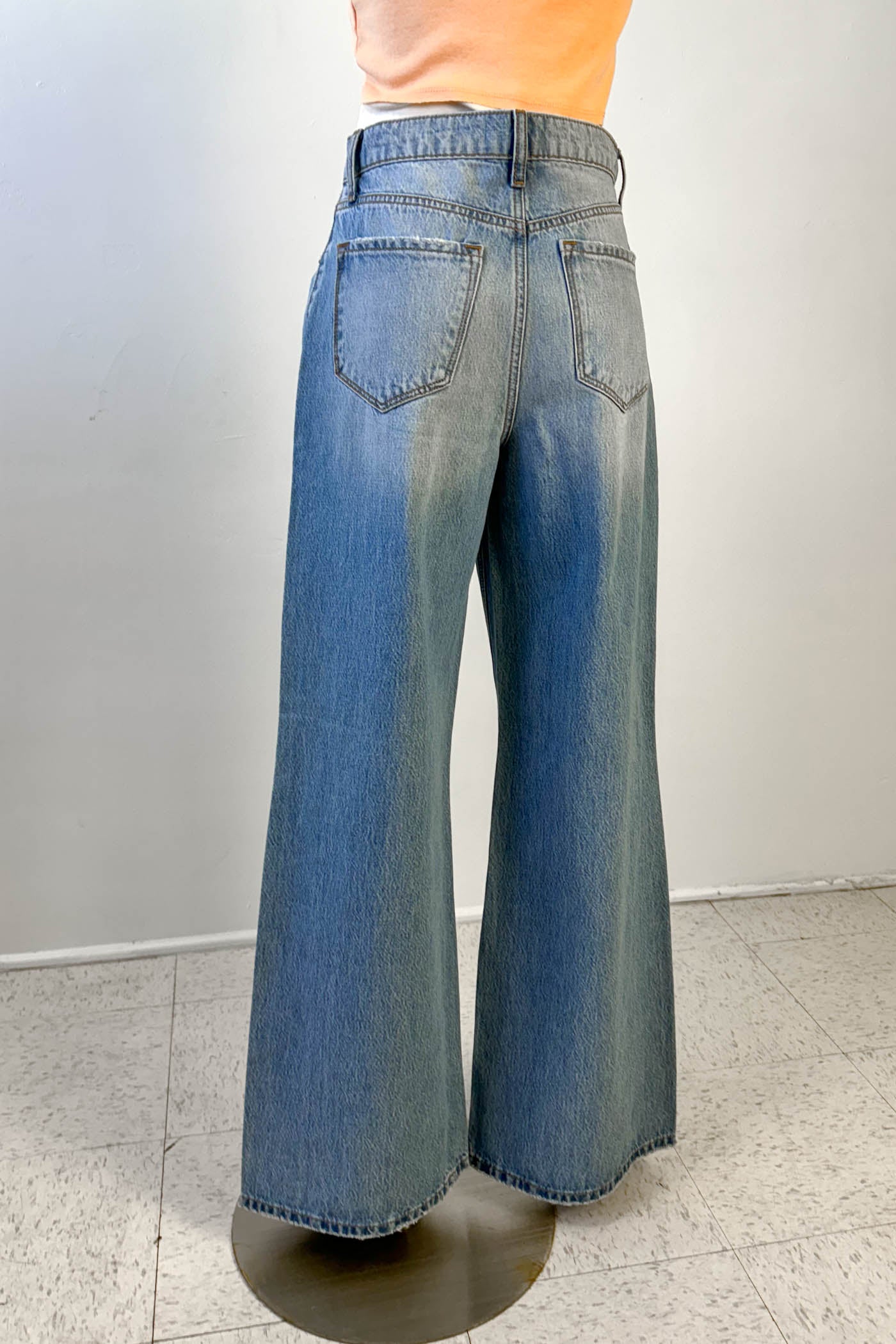 Blue jeans on a stand against a plain background