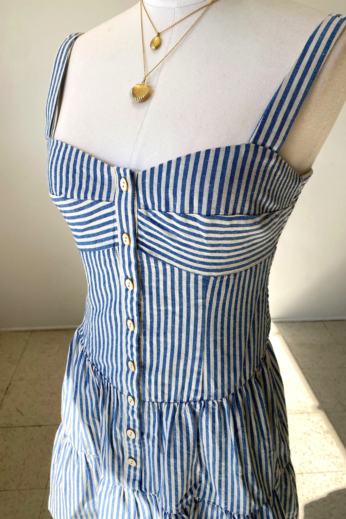 Blue and white striped dress on a mannequin with a plain background