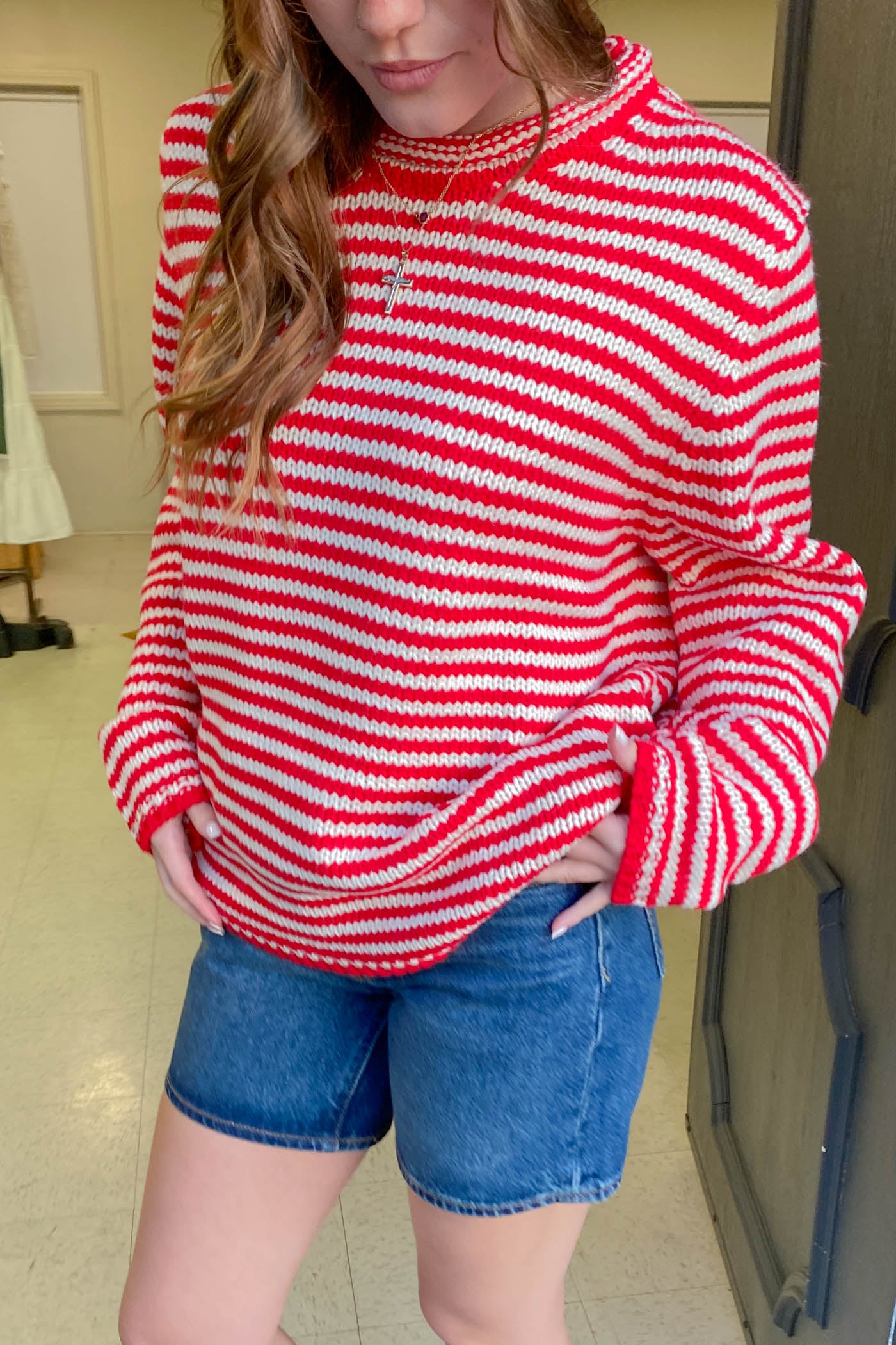 Person wearing a red and white striped sweater and blue shorts indoors.