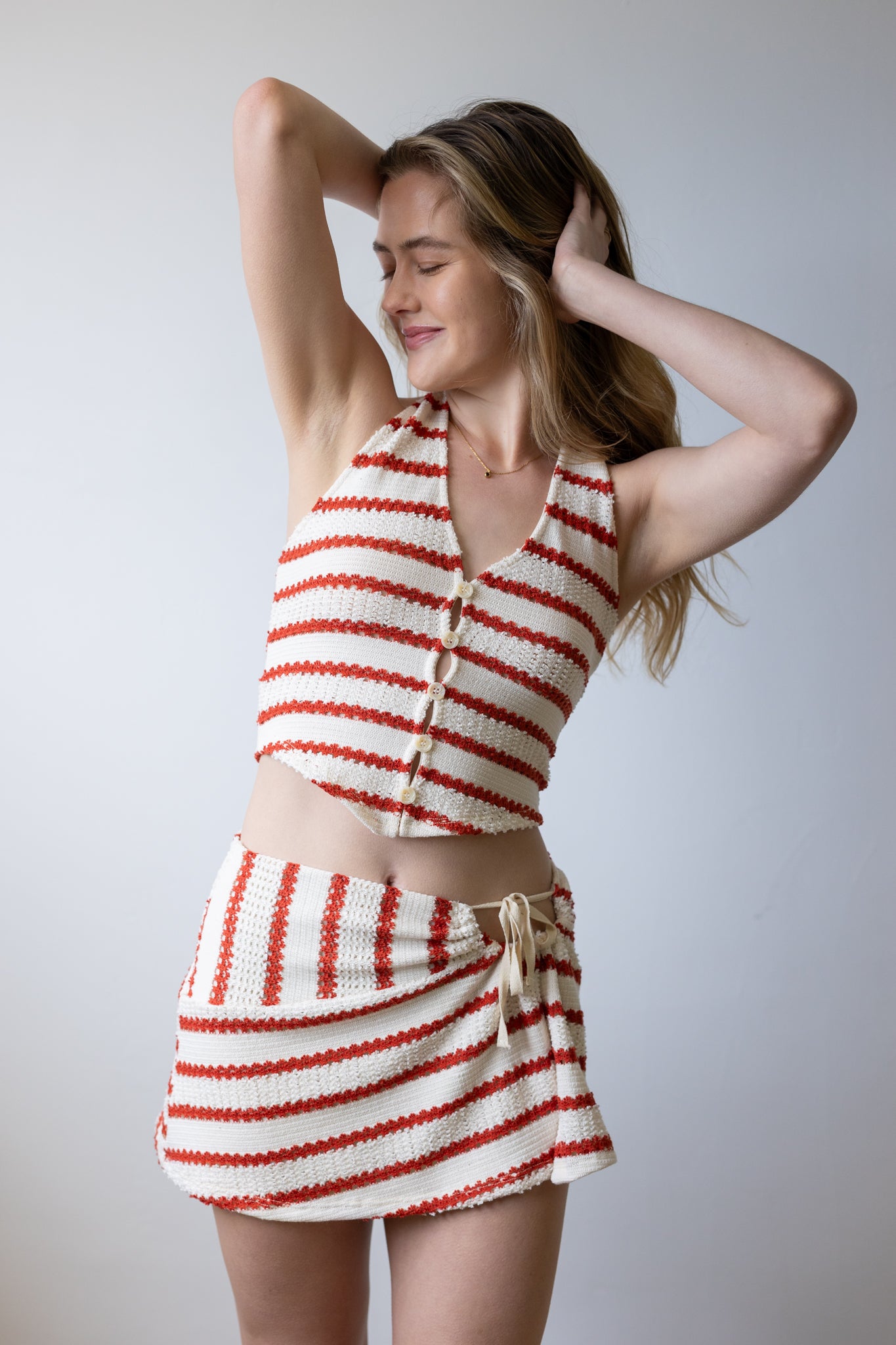Woman wearing a red and white striped outfit against a plain background