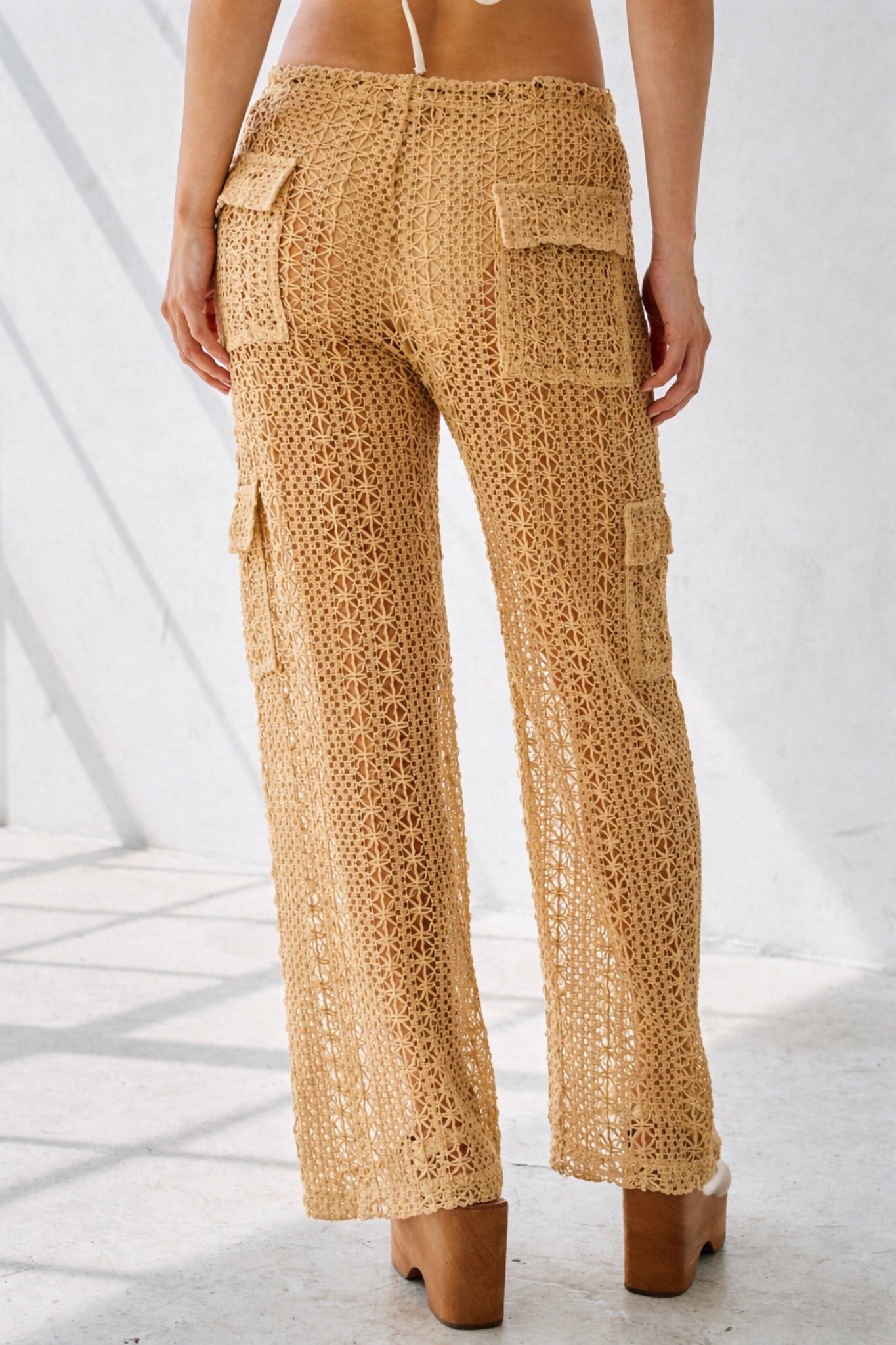 Beige crochet pants worn by a person on a white background