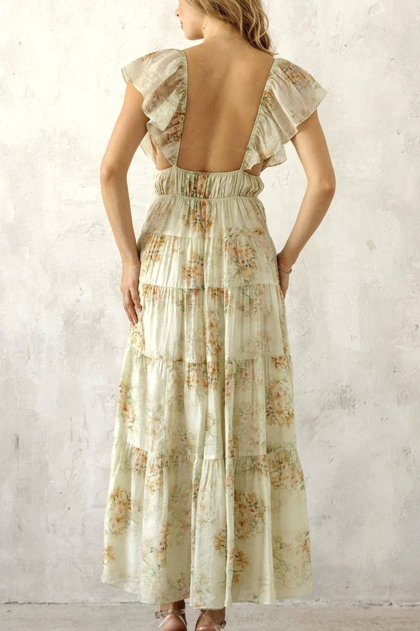 Woman wearing a floral dress with an open back against a light background
