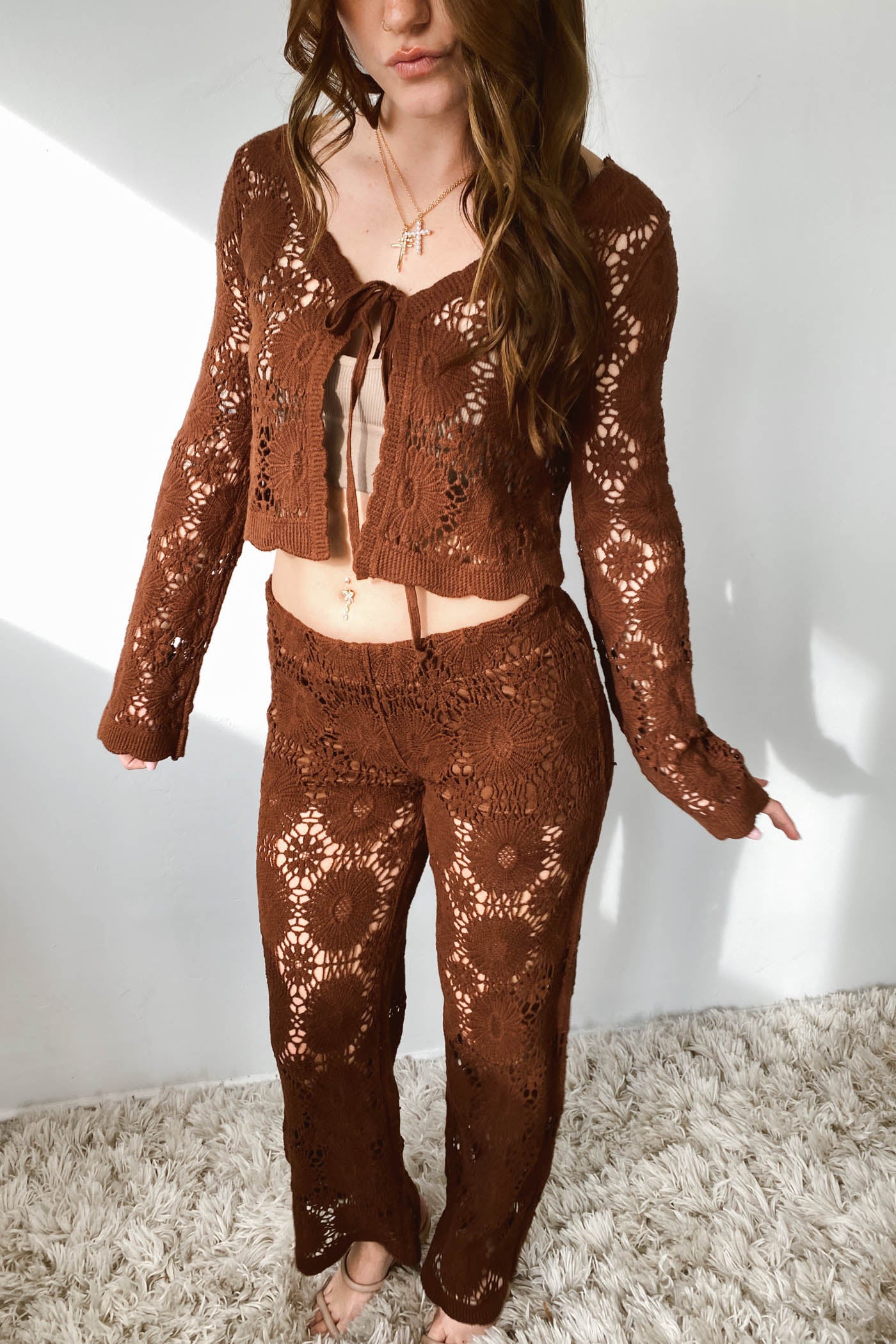 Person wearing a brown crochet outfit on a light background