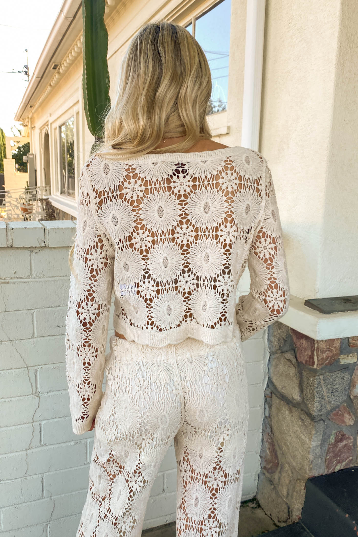 Woman wearing a white lace outfit standing in front of a house.