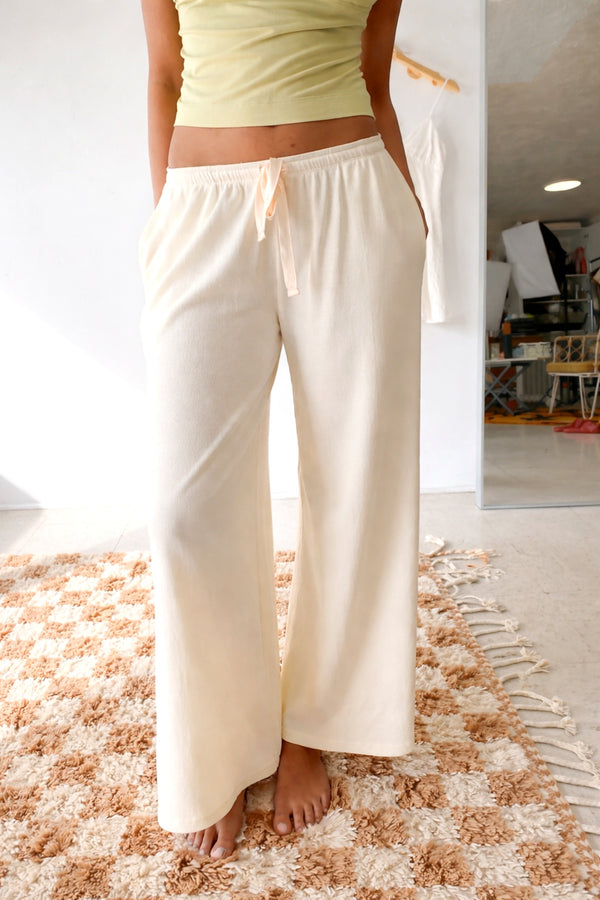 Person wearing light-colored pants standing on a textured rug indoors.