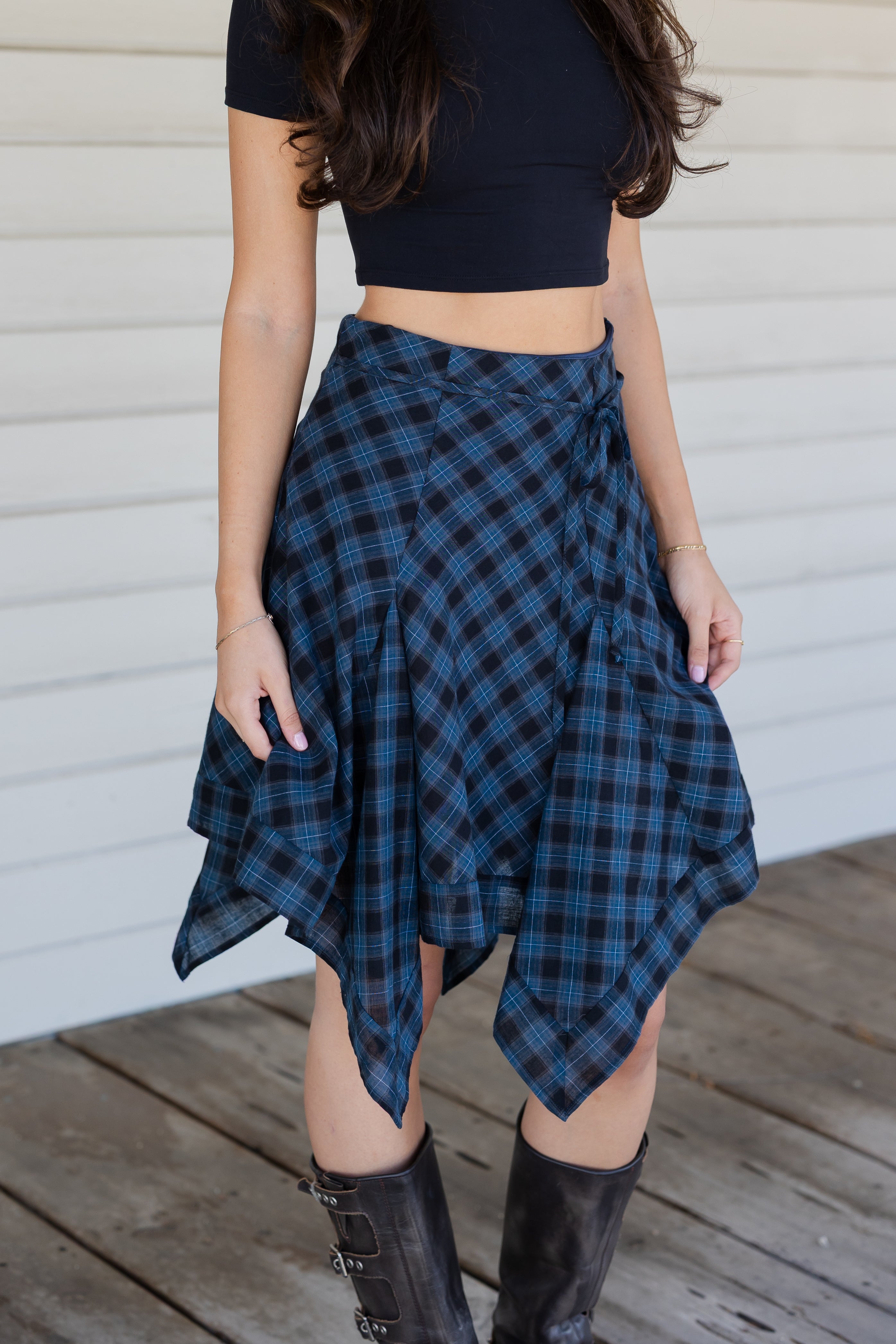 Person wearing a blue plaid skirt on a wooden deck