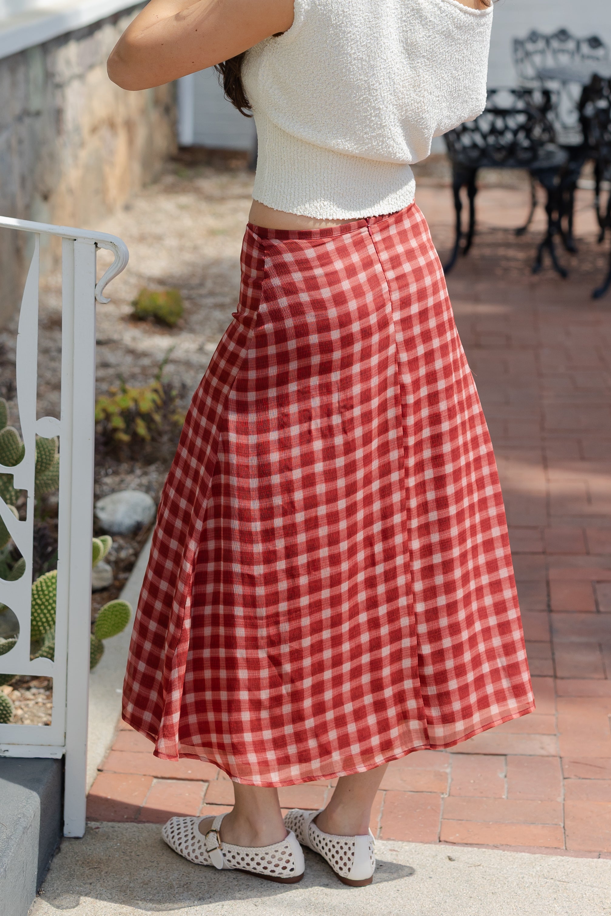 Person wearing a red and white checkered skirt outdoors.
