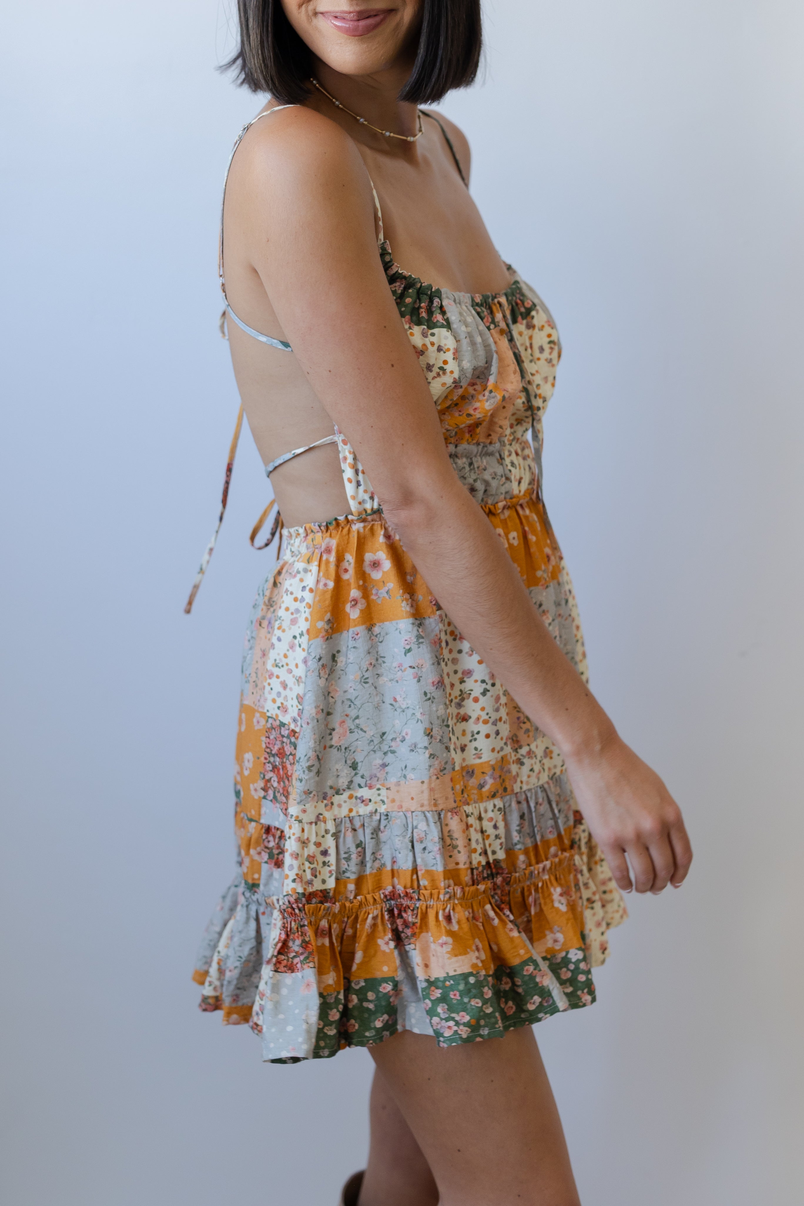 Woman wearing a colorful patchwork dress against a plain background