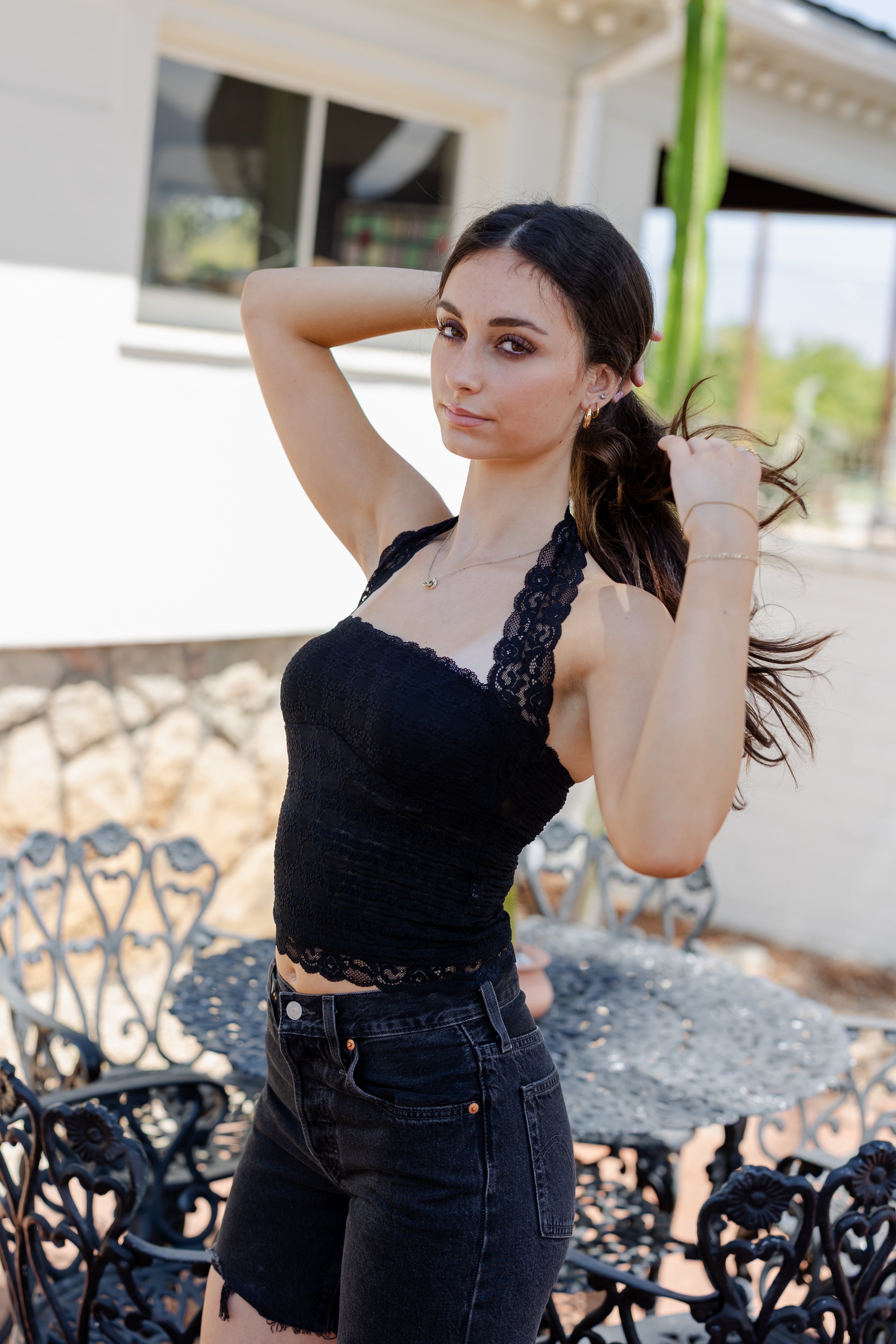 Woman wearing a black lace top and dark jeans outdoors.