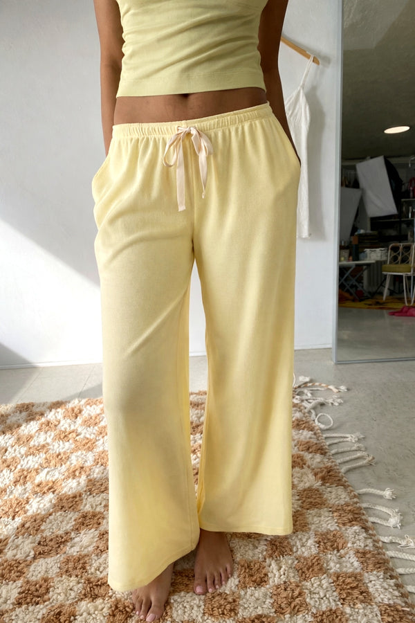 Person wearing light yellow pajama pants standing on a checkered rug.