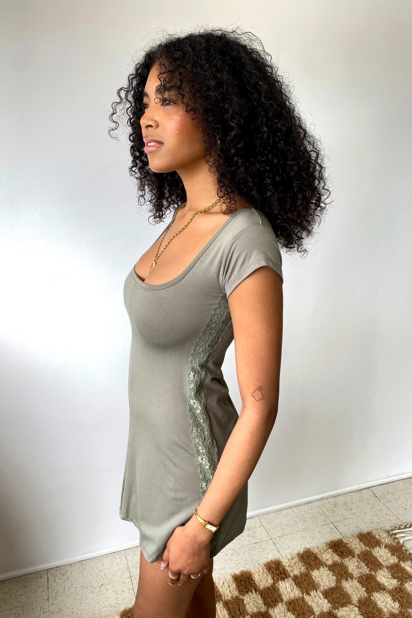 Woman wearing a gray dress with lace details against a plain background