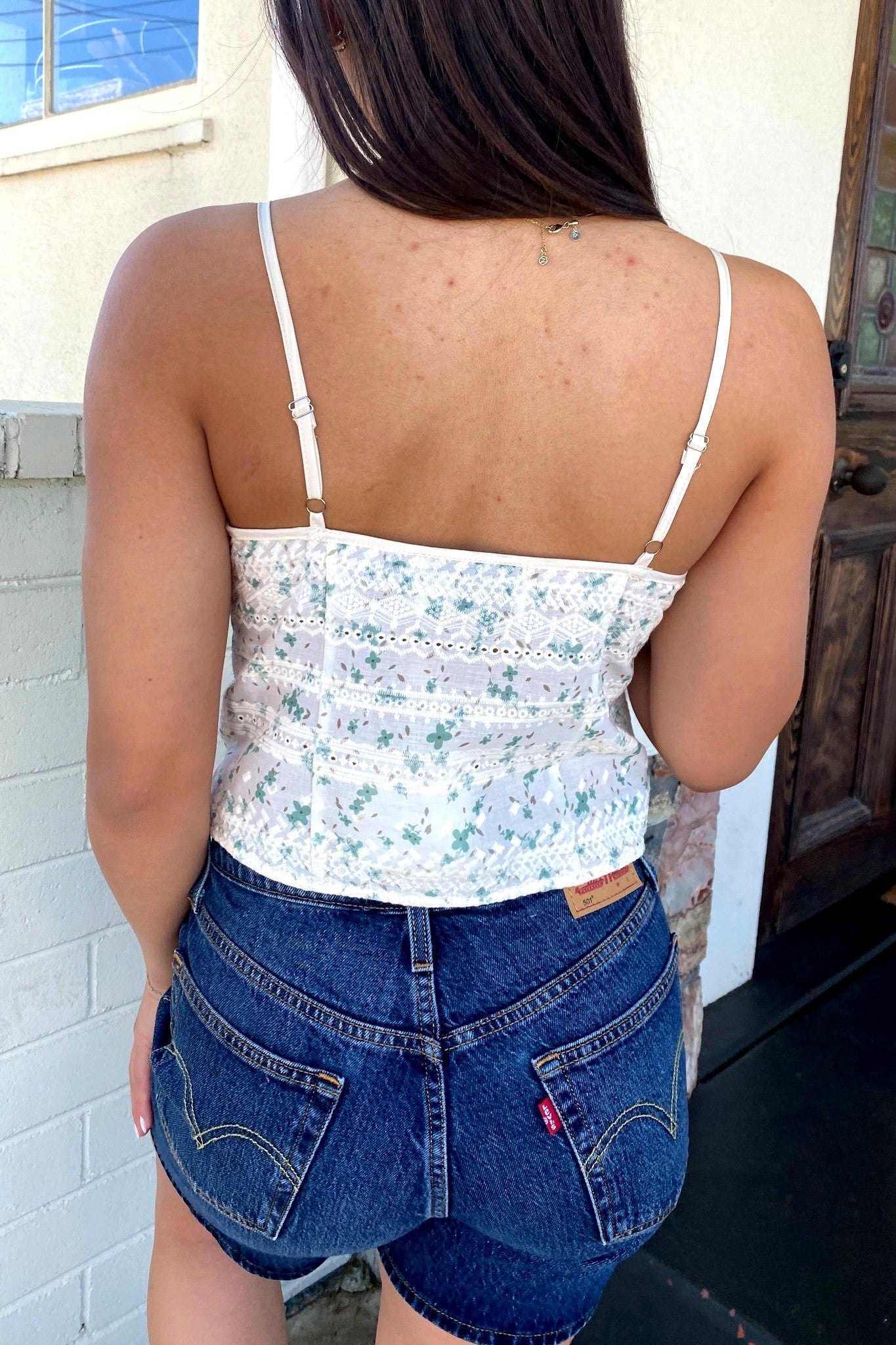 Person wearing a floral top and blue shorts with a building in the background