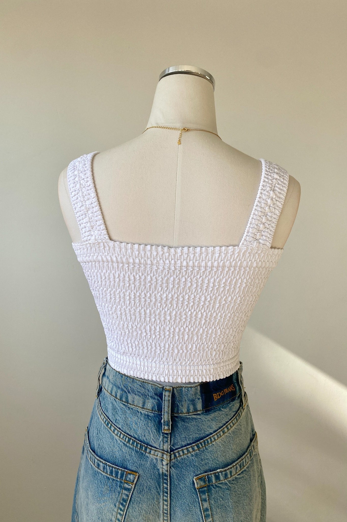 White textured tank top on a mannequin with a plain background
