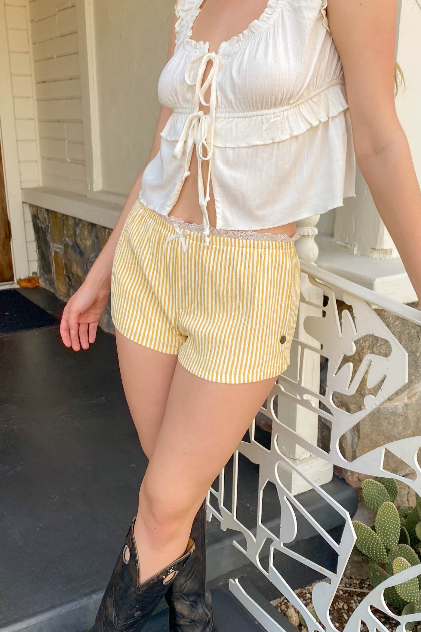Person wearing a white top and yellow striped shorts standing on a staircase.
