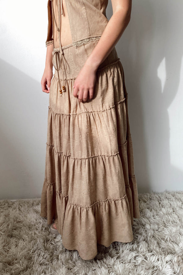 Long beige dress with tiered layers on a white background