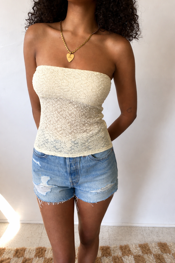 Woman wearing a strapless top and denim shorts against a plain background