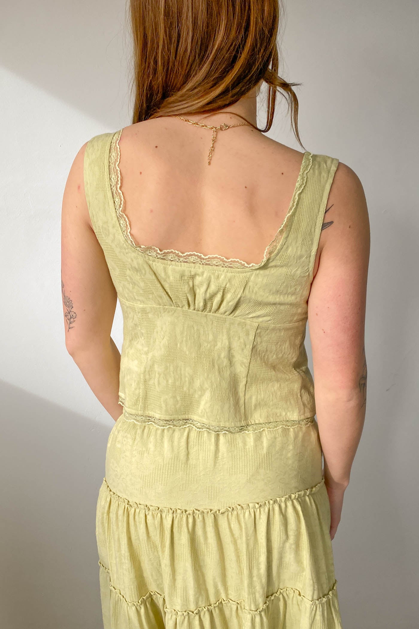Person wearing a light green dress with a plain background