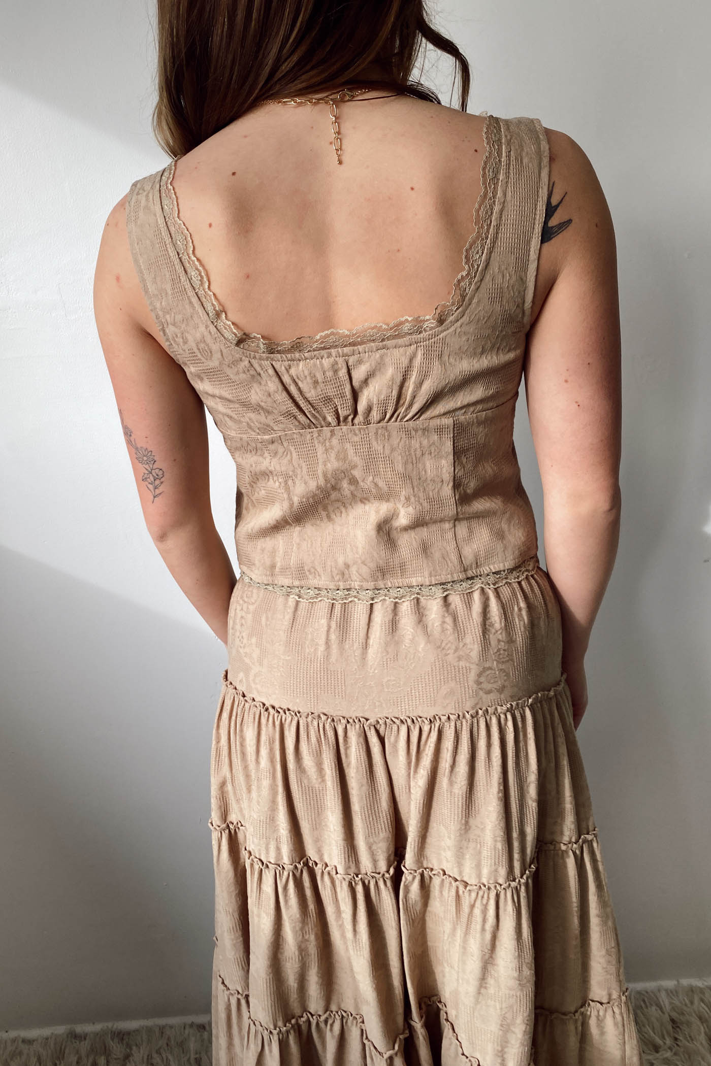 Person wearing a beige dress with a plain background