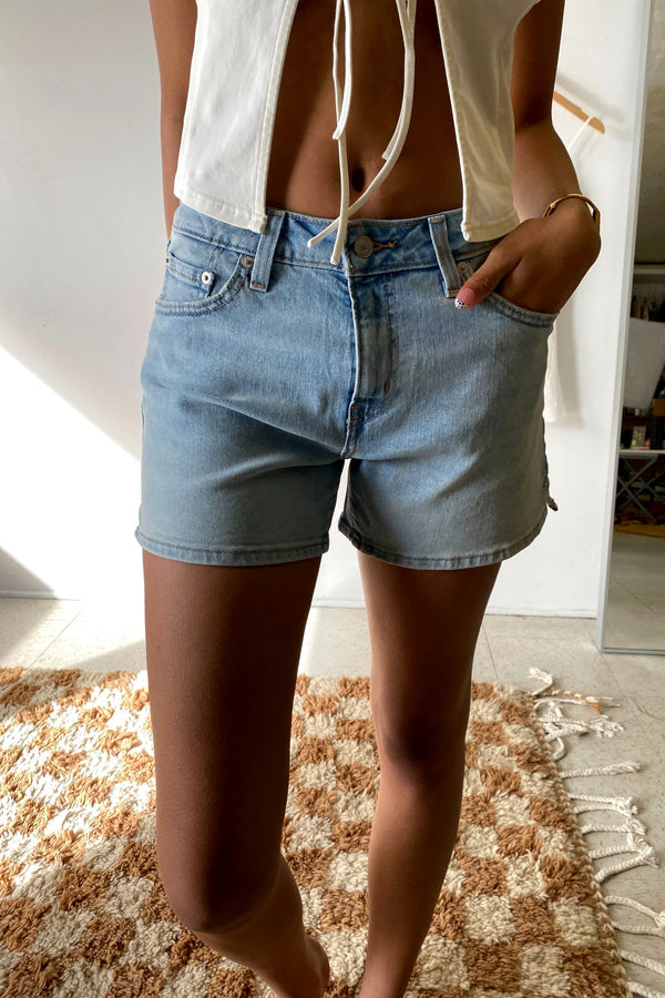 Person wearing light blue denim shorts indoors on a checkered floor.