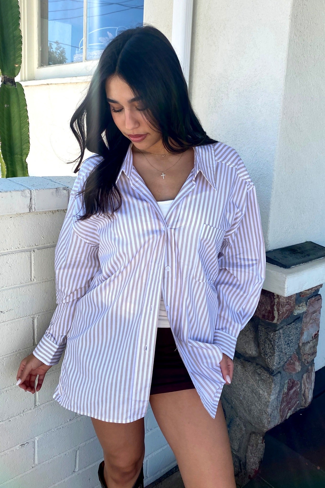 Woman wearing a striped shirt and shorts standing on a porch.
