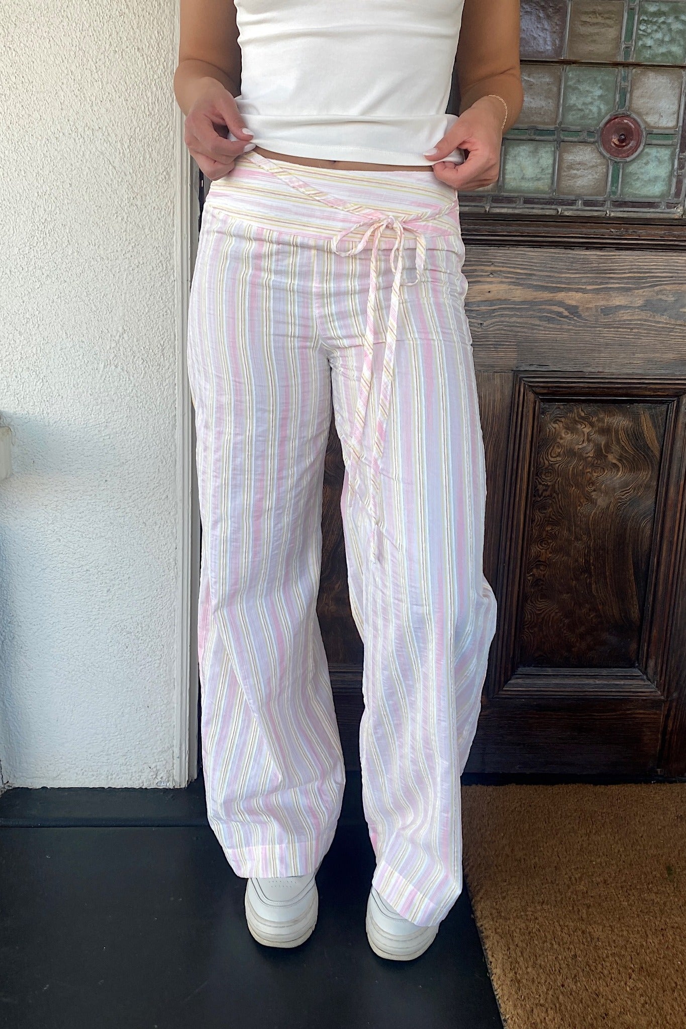 Person wearing white striped pants with a plain background