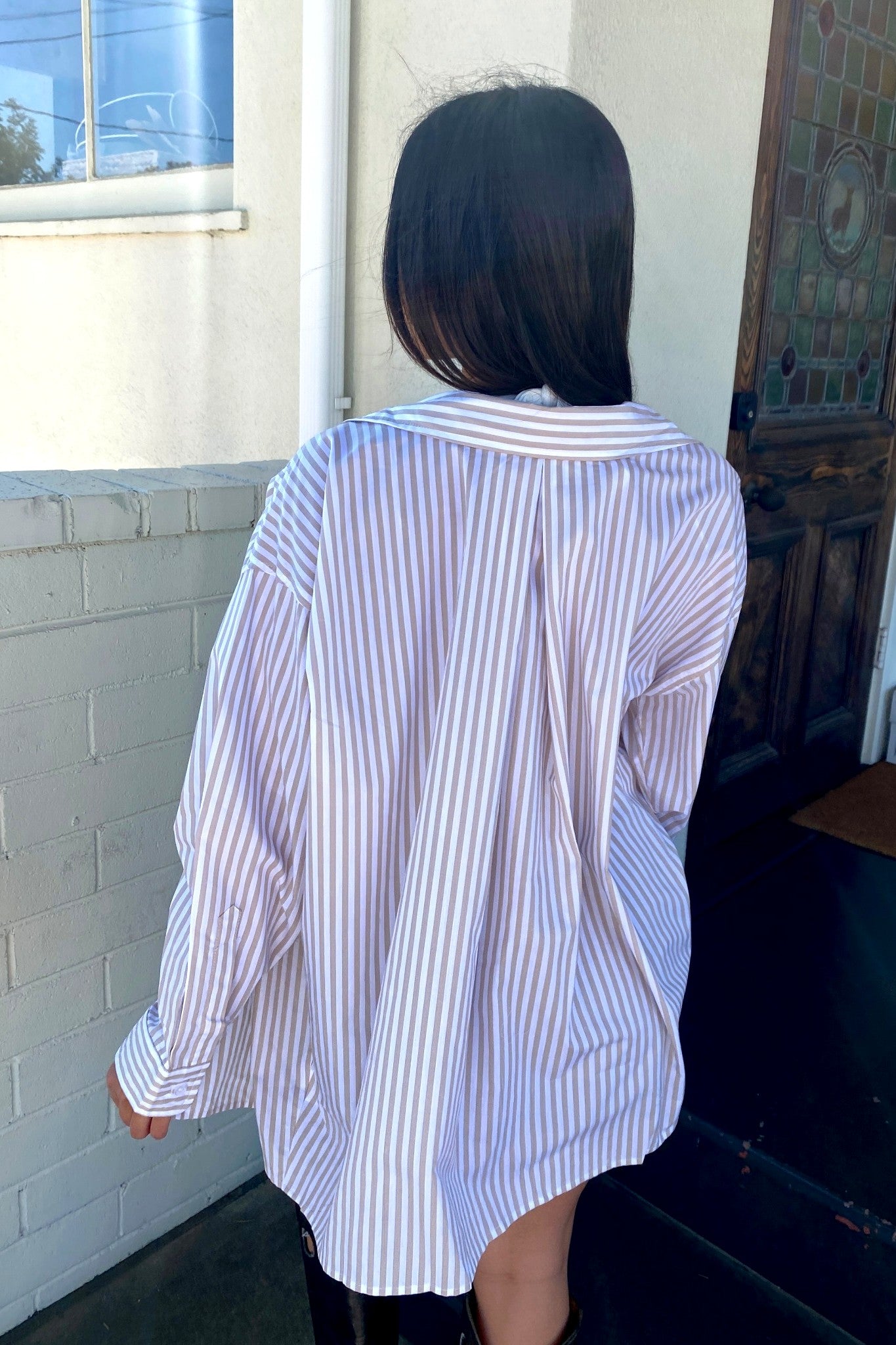 Person wearing a white and blue striped shirt standing in front of a building.