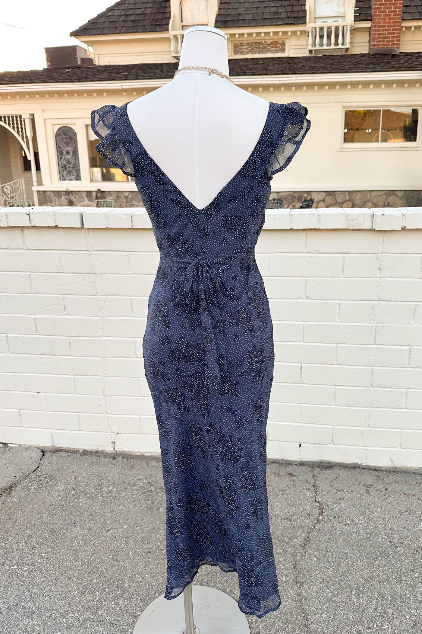 Navy lace dress on a mannequin with a house in the background