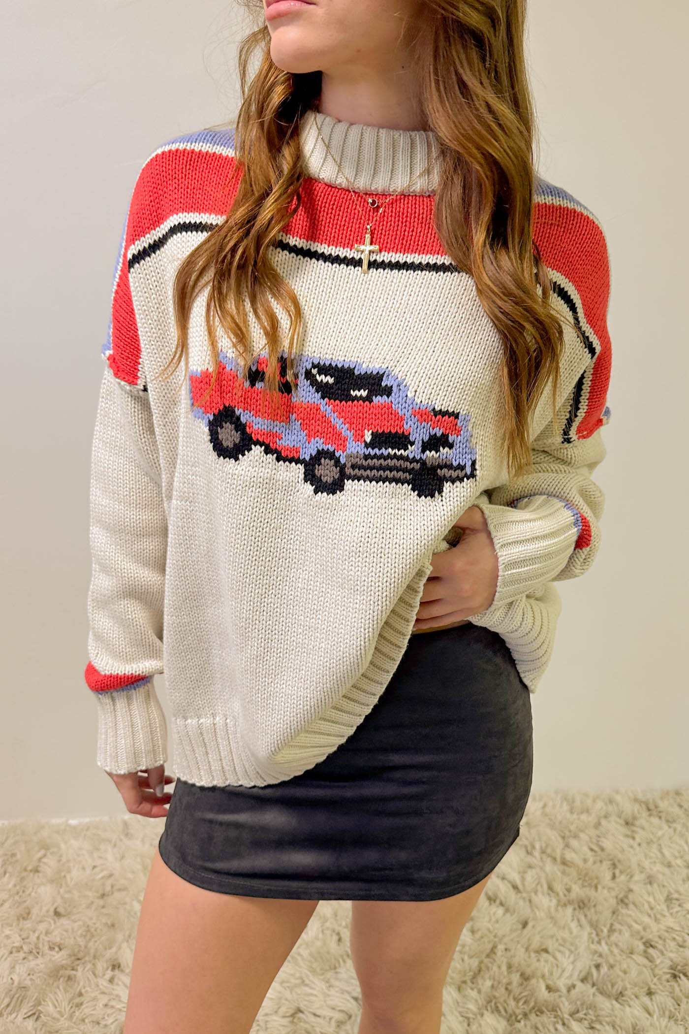 Person wearing a sweater with a car design on a plain background