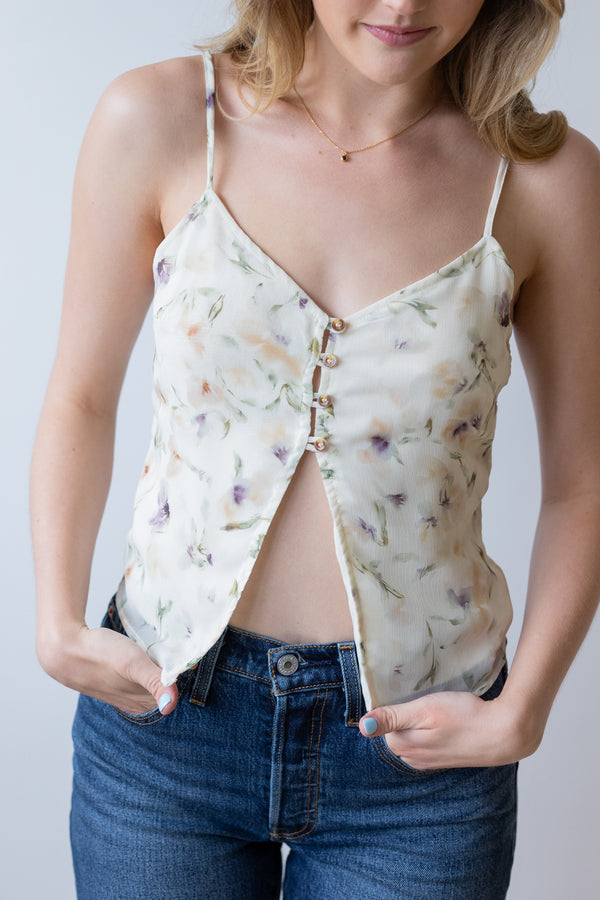Woman wearing a floral camisole over a plain top with a neutral background