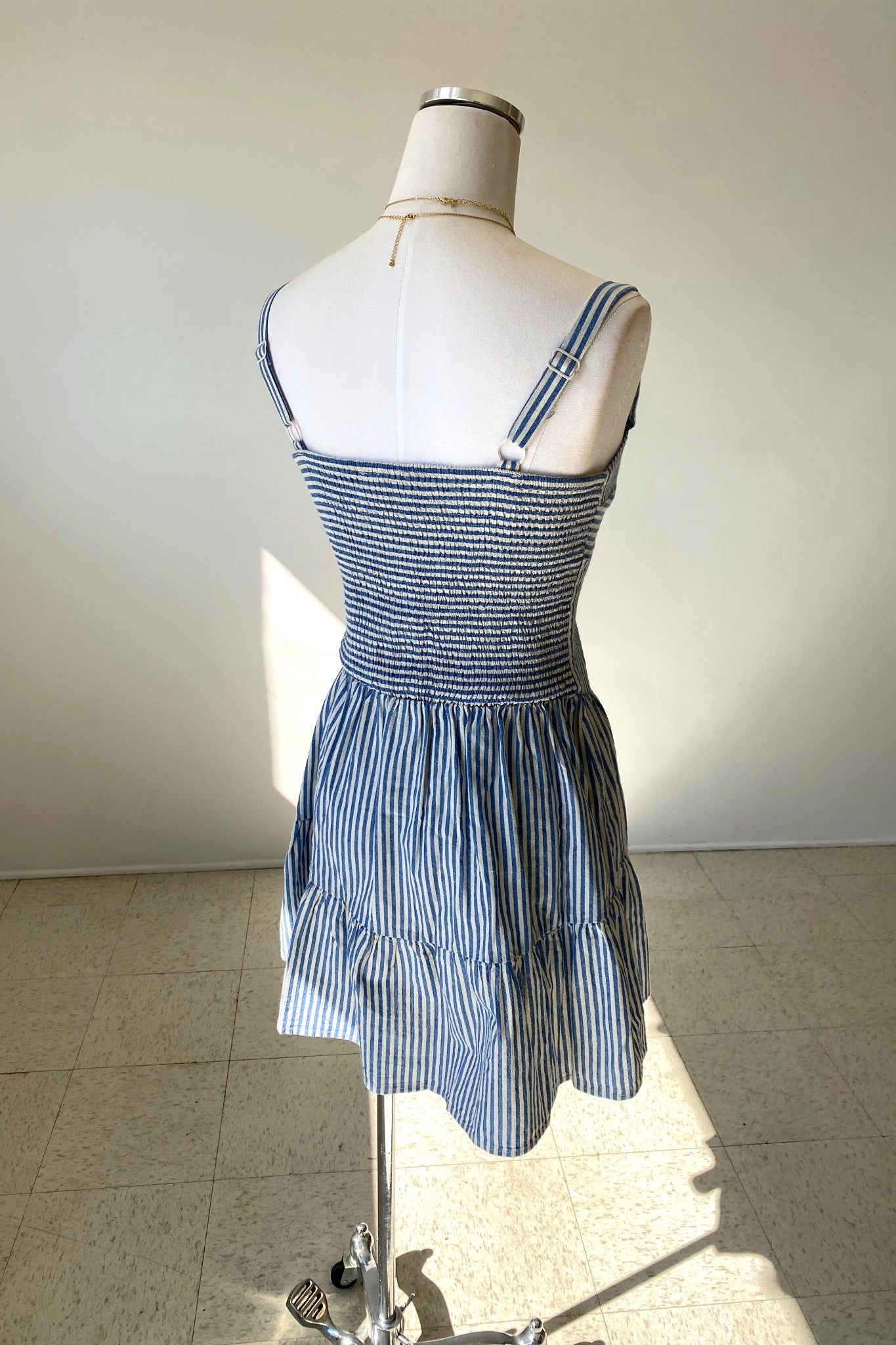 Blue and white striped dress on a mannequin against a plain background
