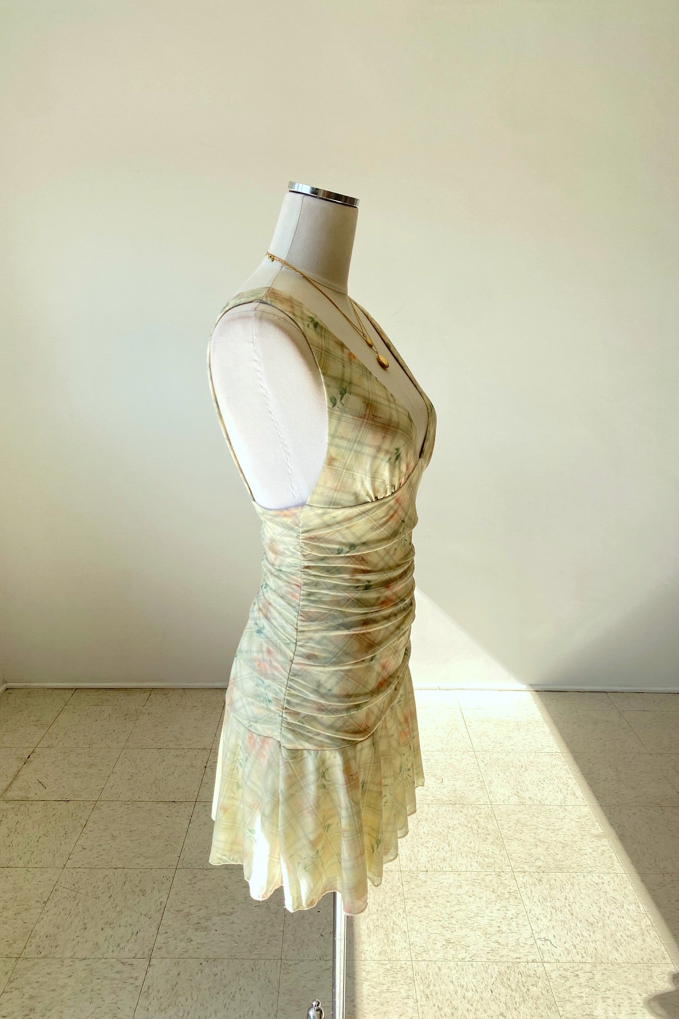 Mannequin wearing a sleeveless dress with a floral pattern on a plain background