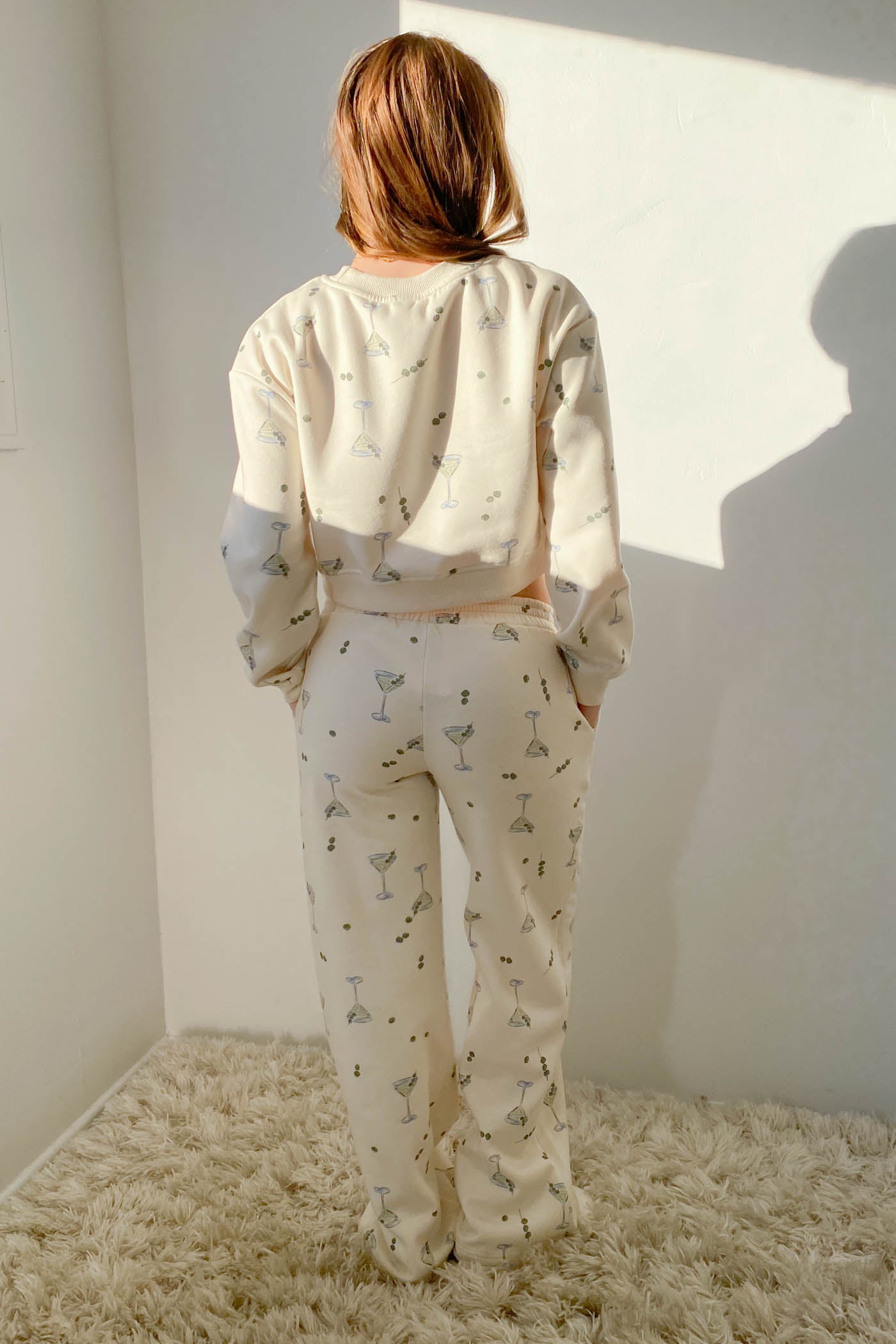 Person wearing a patterned pajama set standing in a room with a textured floor and white walls.