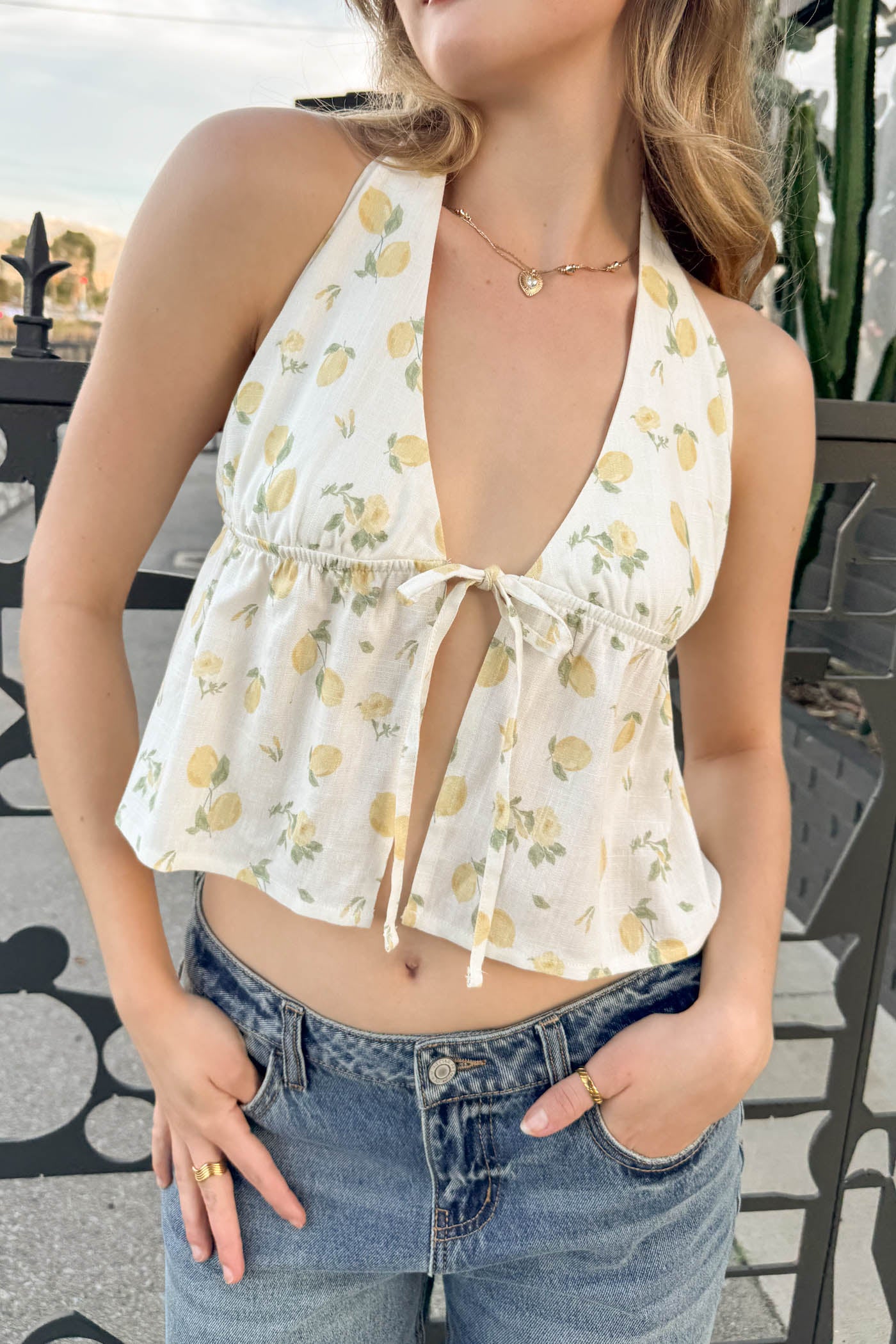 Woman wearing a floral halter top and denim shorts outdoors.