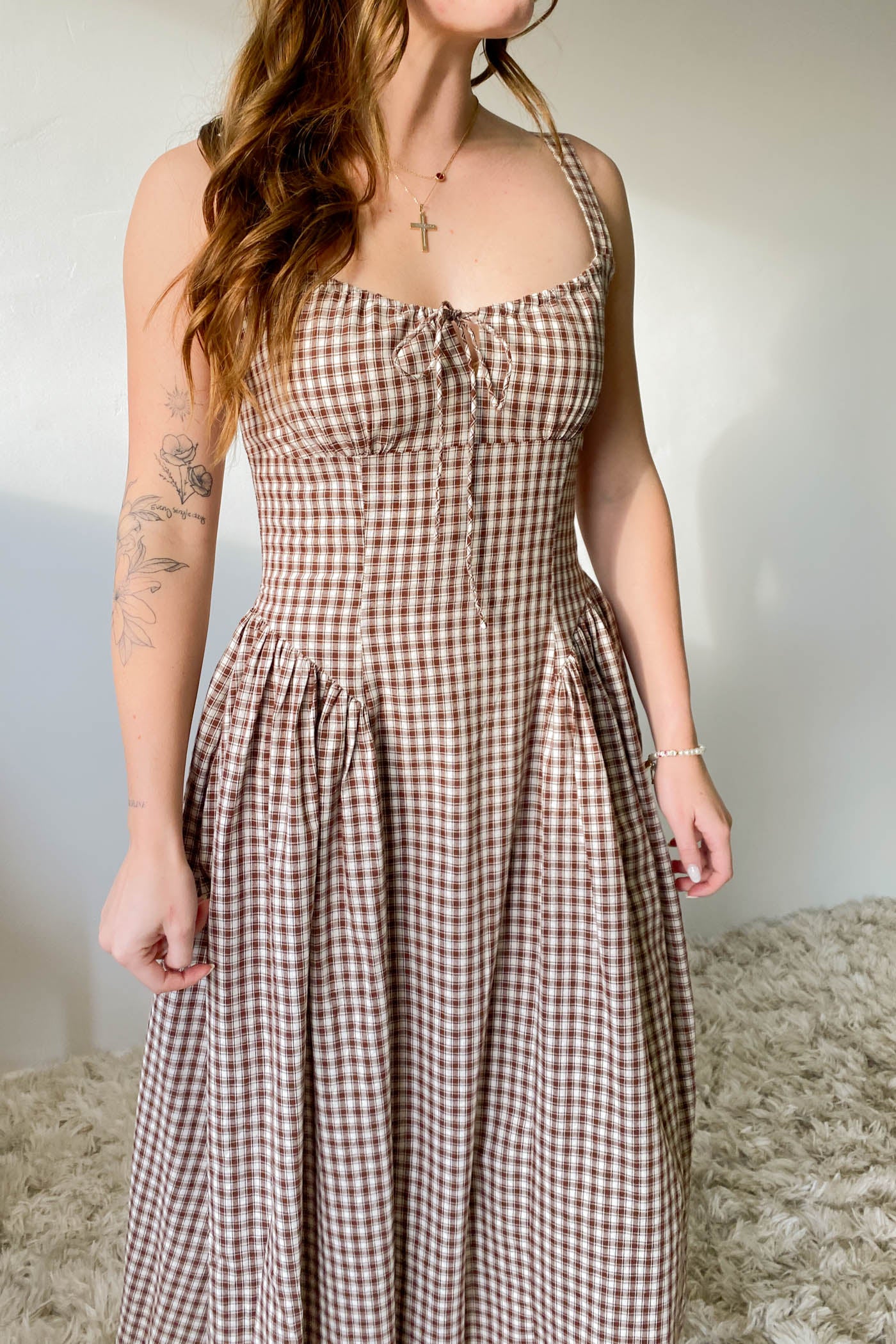 Woman wearing a checkered dress with a neutral background
