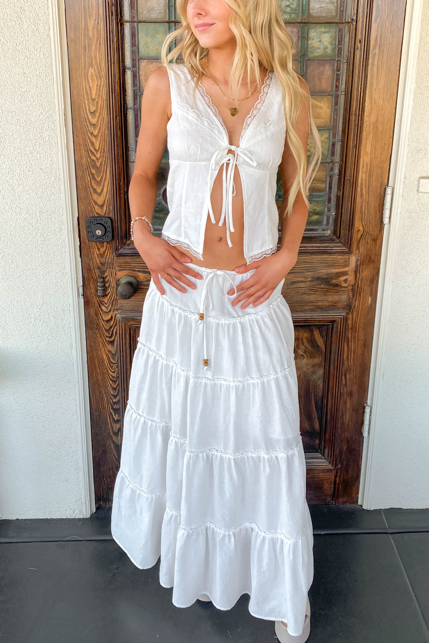 Woman wearing a white dress standing in front of a wooden door.