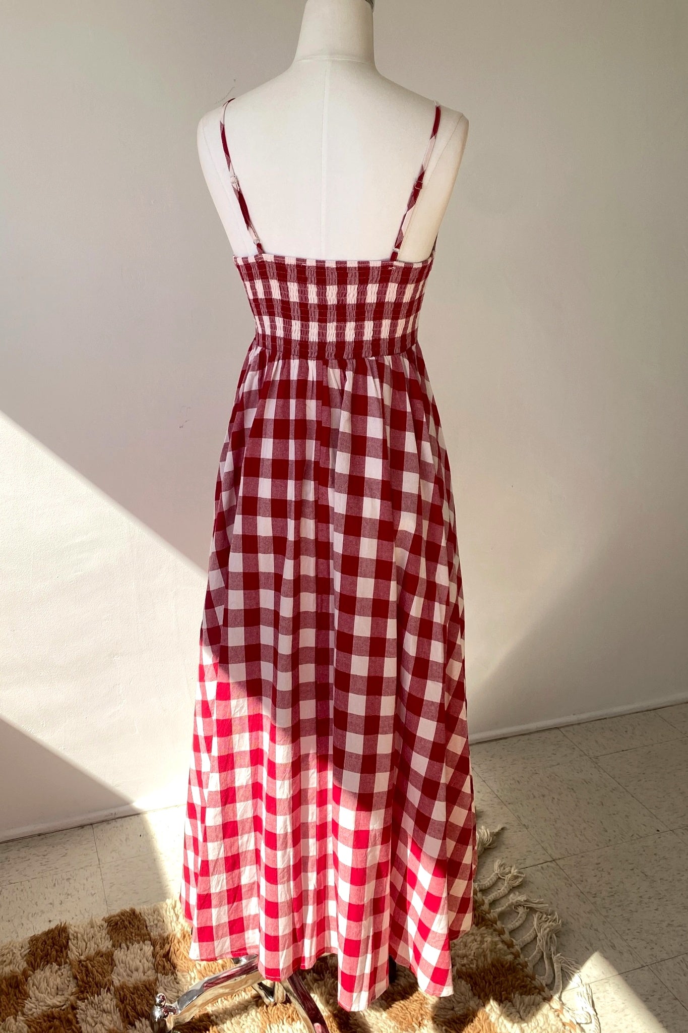 Red and white checkered dress on a mannequin against a plain background
