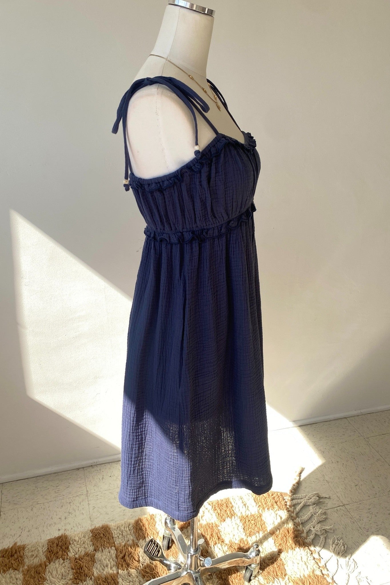 Navy blue dress on a mannequin against a neutral background
