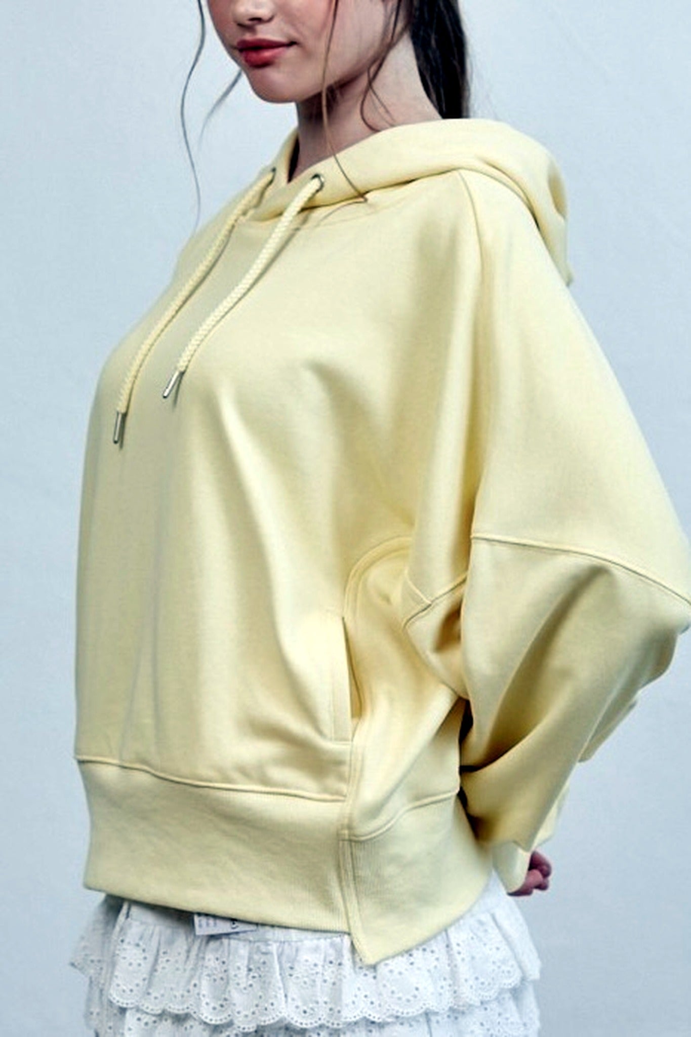 Person wearing a light yellow hoodie against a plain background
