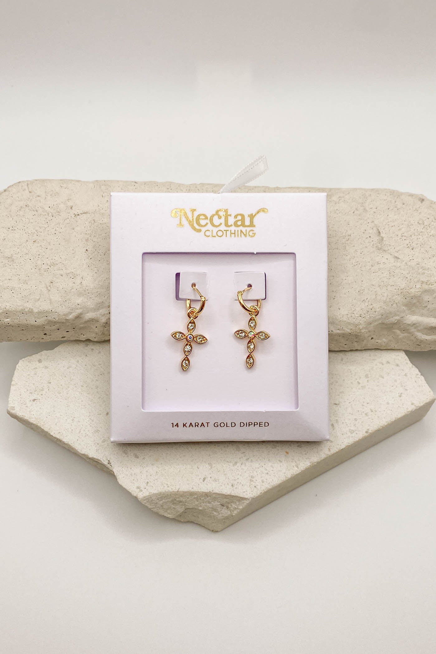 Gold cross earrings on a Nectar Clothing branded card with a stone background