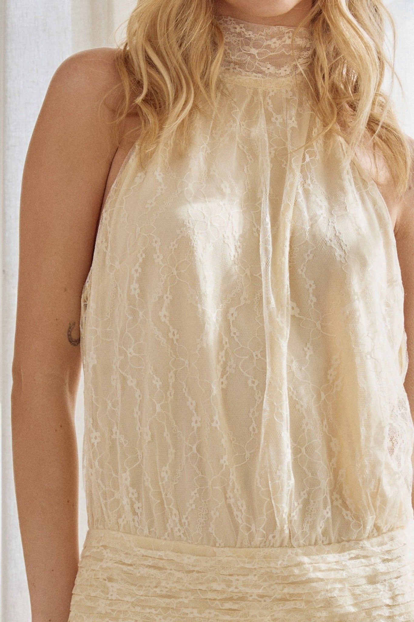 Beige lace halter neck dress worn by a person with blonde hair.