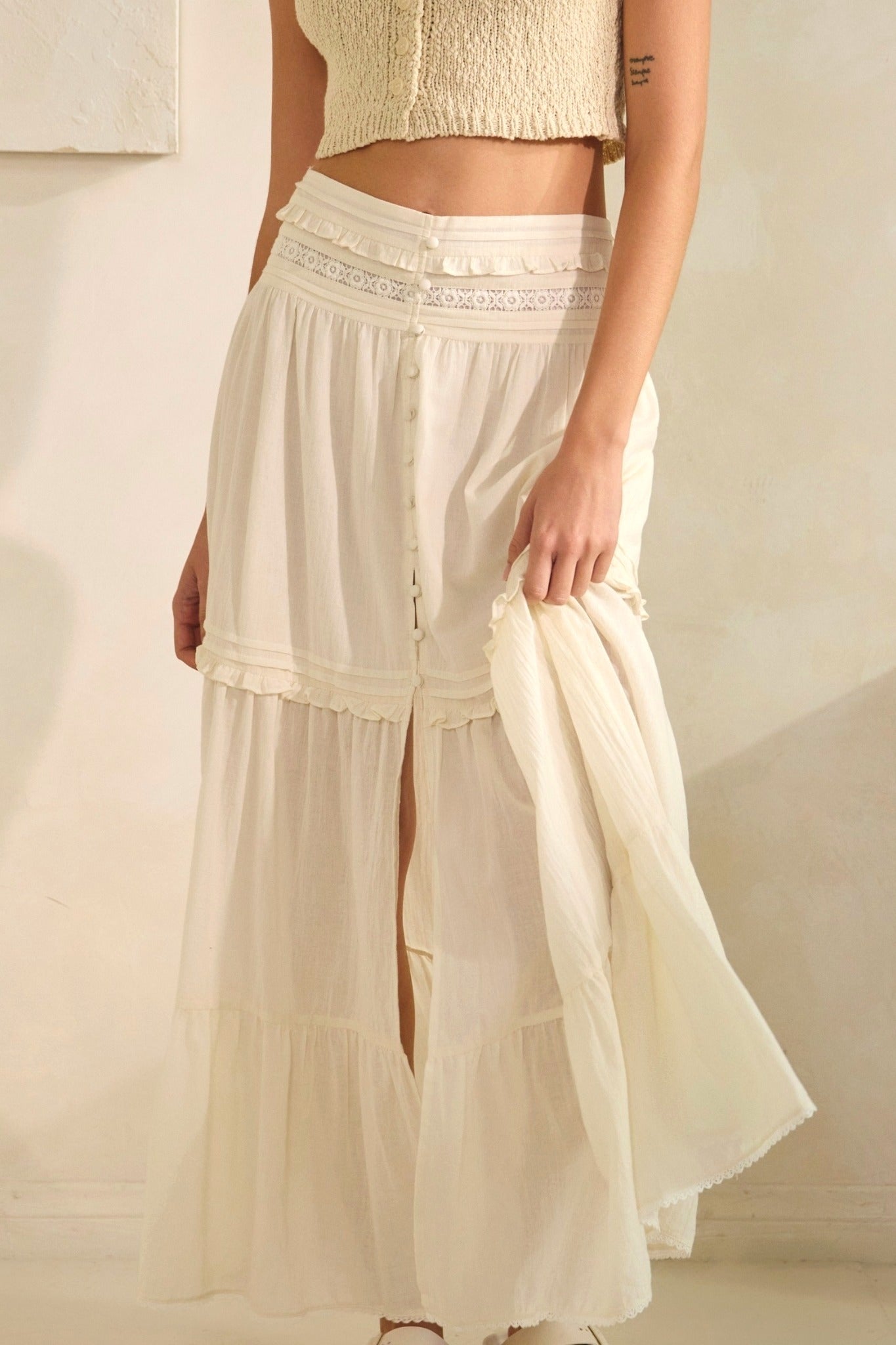 Person wearing a flowing beige skirt with a plain background