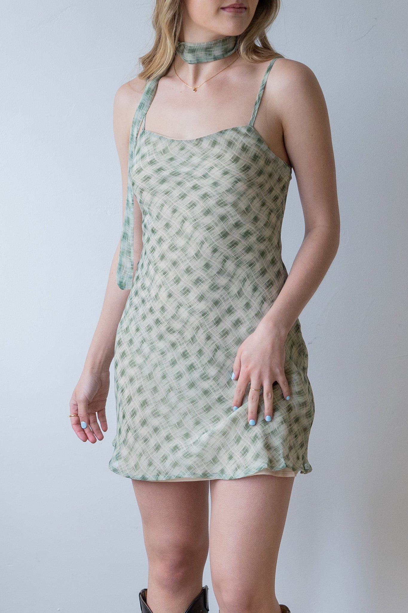 Woman wearing a green patterned dress against a plain background