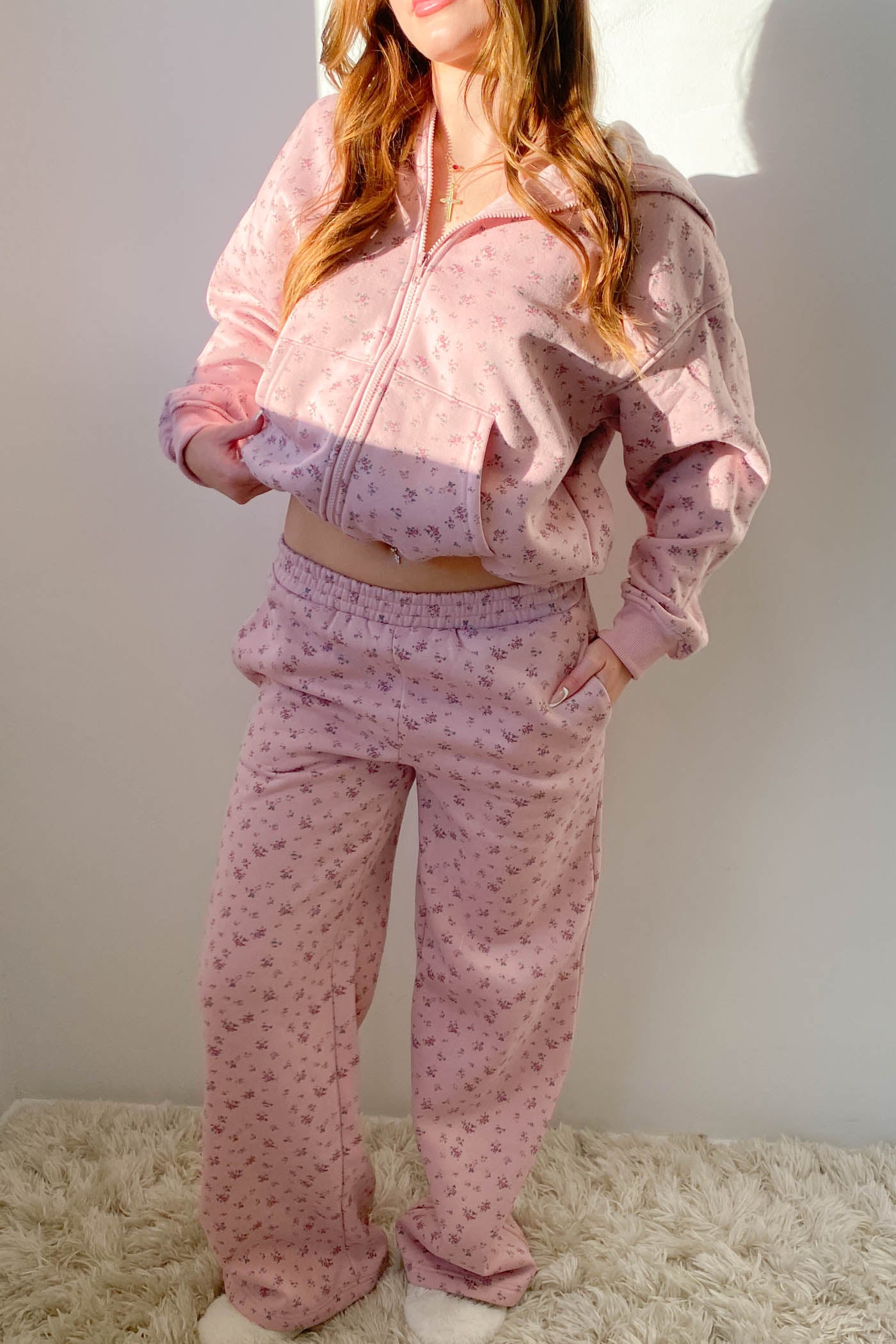 Person wearing a pink pajama set with a pattern against a plain background