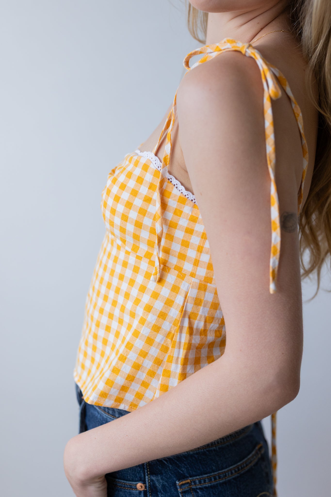 Yellow checkered top worn by a person against a plain background