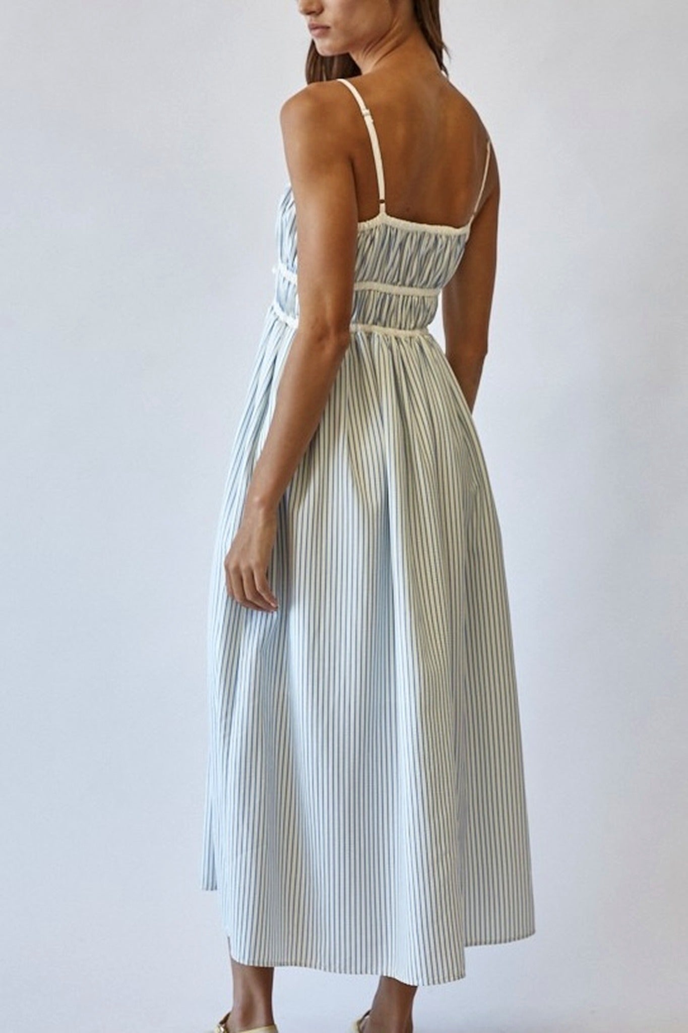 Woman wearing a striped dress against a plain background